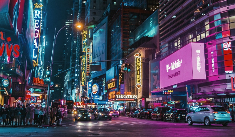 New York City lit up at night, with many neon signs.