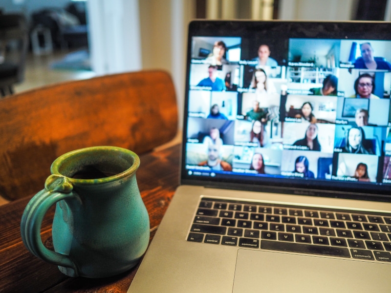 Coffee mug next to an open laptop displaying a Zoom meeting