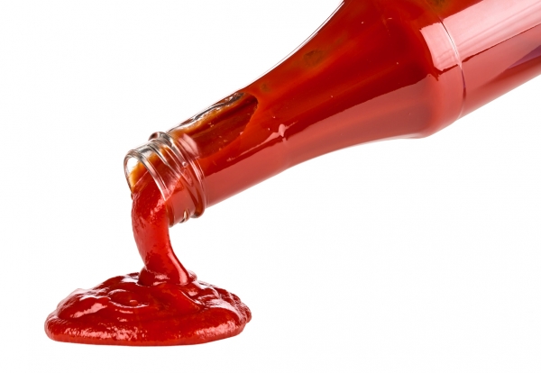 Ketchup pouring out of a glass ketchup bottle