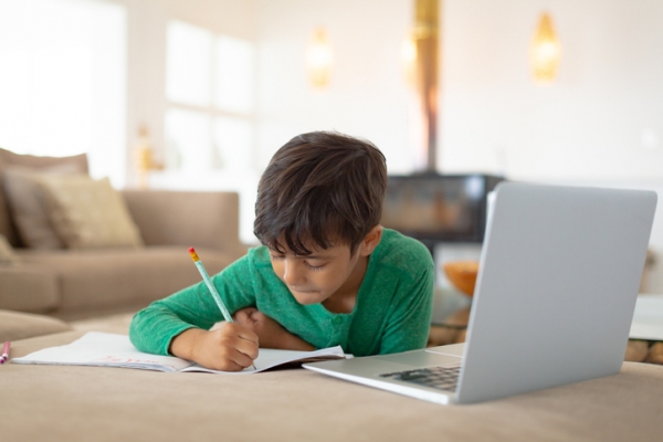 Boy drawing beside laptop at home