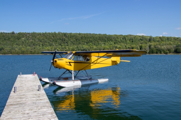 Shown is a colour photograph of a small plane floating next to a dock.