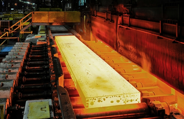 Shown is a colour photograph of a long, yellow, glowing rectangle on metal rollers.