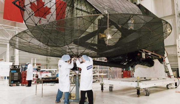 Shown is a colour photograph of two people working at the bottom of a huge dish-shaped object. 