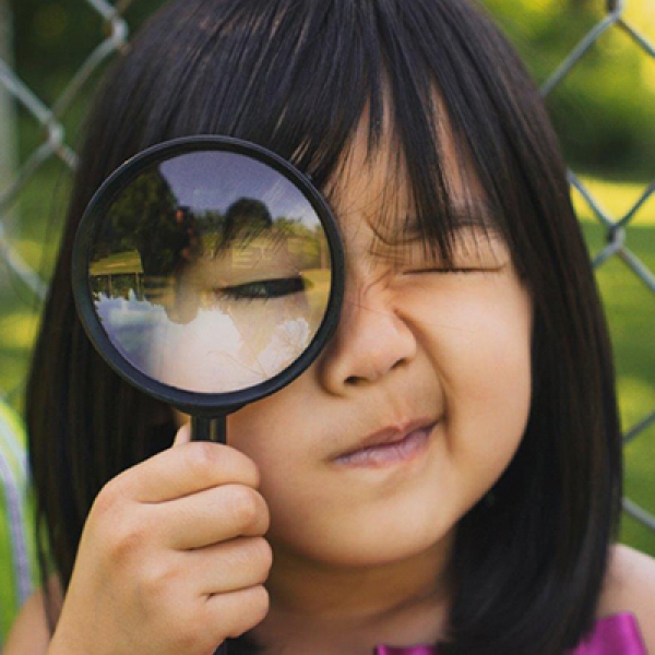 Student looking through magnifying glass