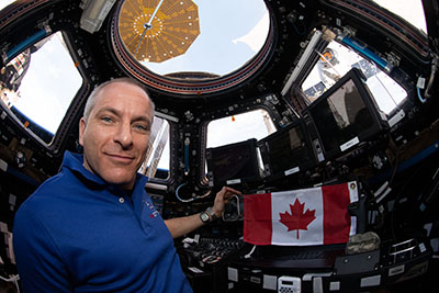 
			Astronaut David Saint-Jacques aboard the International Space Station with a Canadian flag 